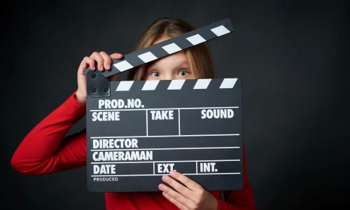 Mädchen hällt eine Filmklappe in der Hand